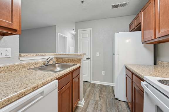 A kitchen with white appliances and brown cabinets.